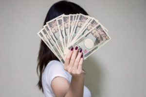 お金で顔を隠す女性画像